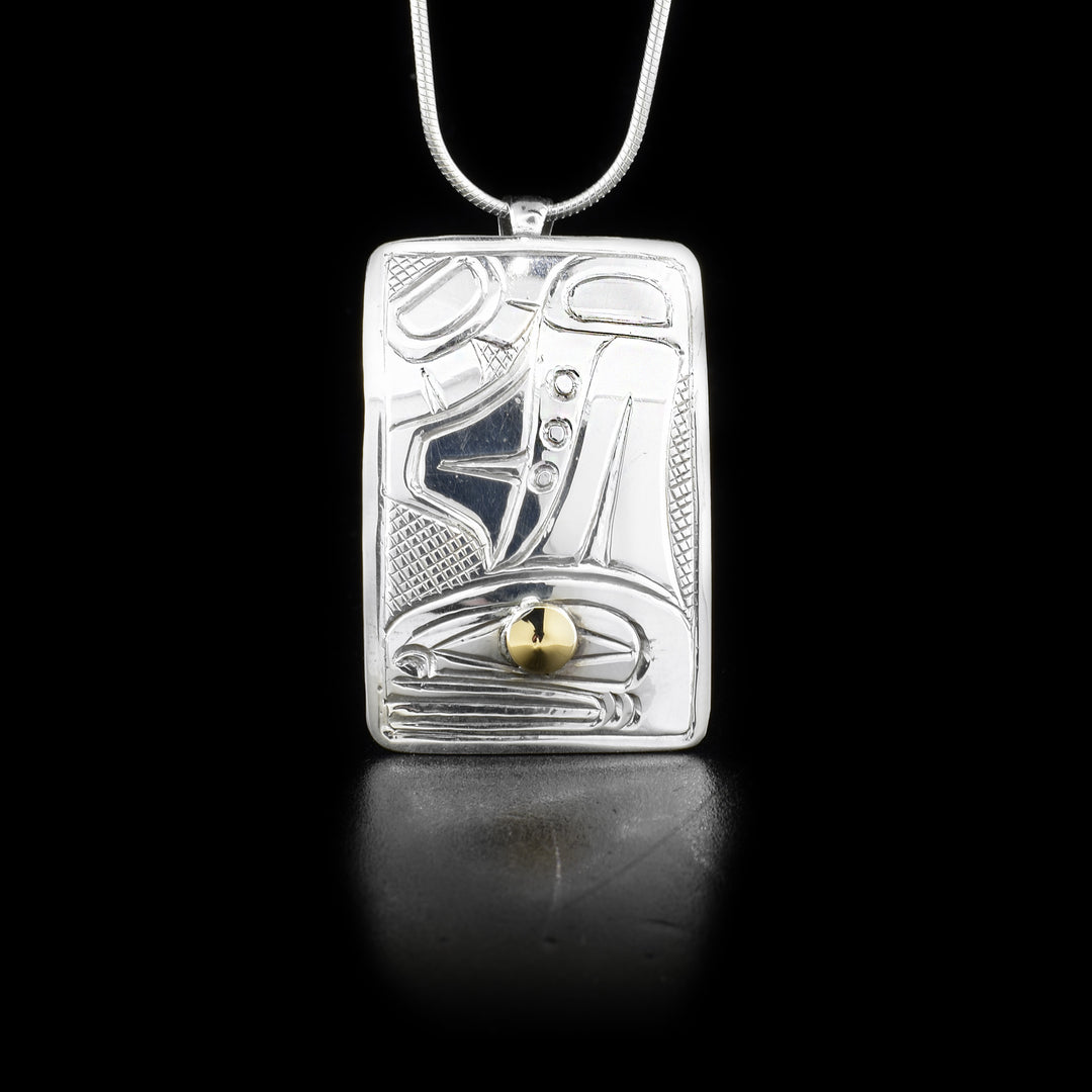 Sterling silver rectangular pendant featuring orca with 14K yellow gold in eye. Cross-hatching background. By Heiltsuk artist Reg Gladstone.