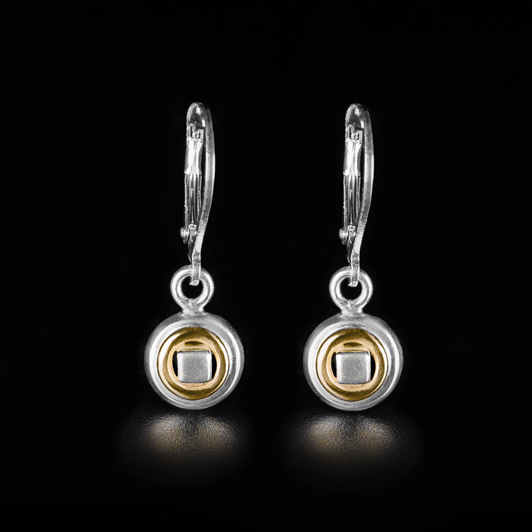 These drop circle in circle earrings are made form sterling silver and 14K gold. The hangs are small, circular and have gold, ring highlights in them. There is a silver square held in the center cutout.