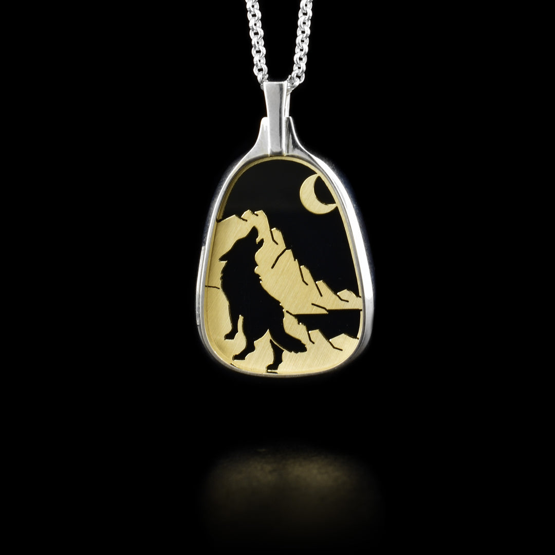 Sterling silver and 14K yellow gold wolf howling at moon black onyx pendant with cut-out background.