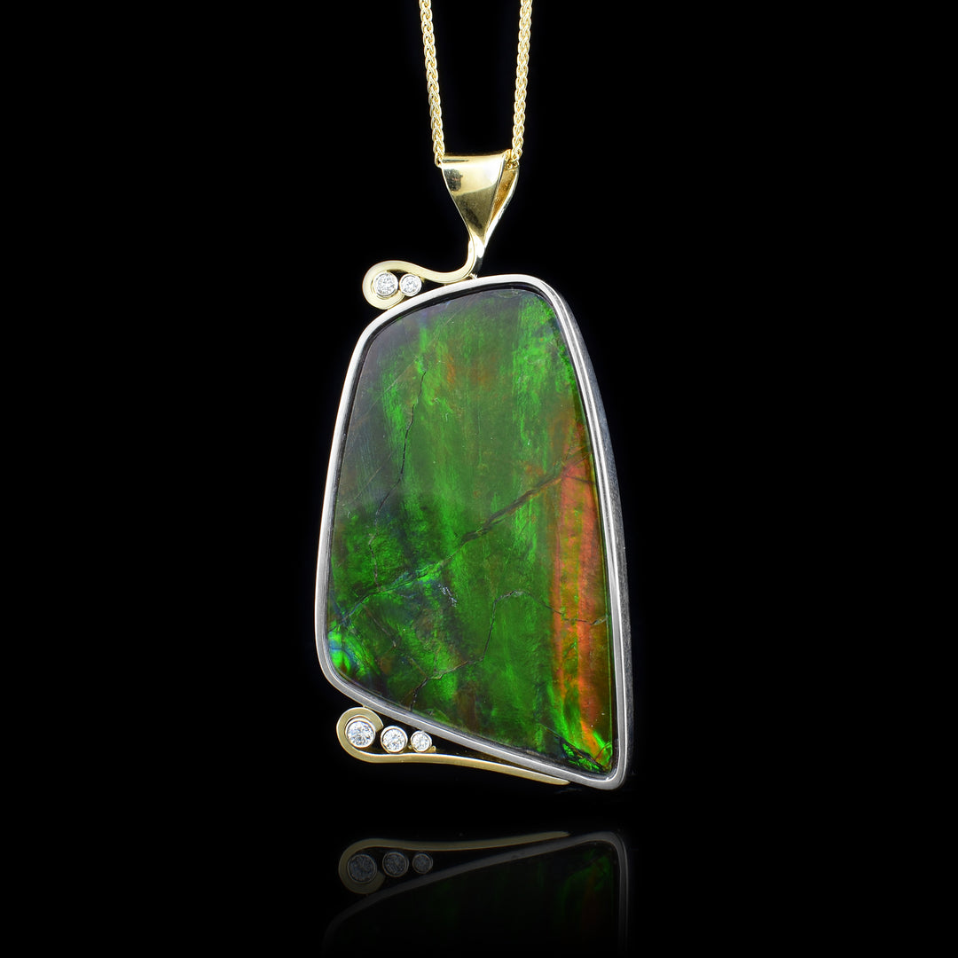 Silver, Gold and Diamond Ammolite Pendant. This unique pendant has a large ammolite stone set in a sterling silver frame surrounded by 14k accents with 3 diamond enveloped on the bottom and 2 diamonds framed in a swirl of 14k gold.