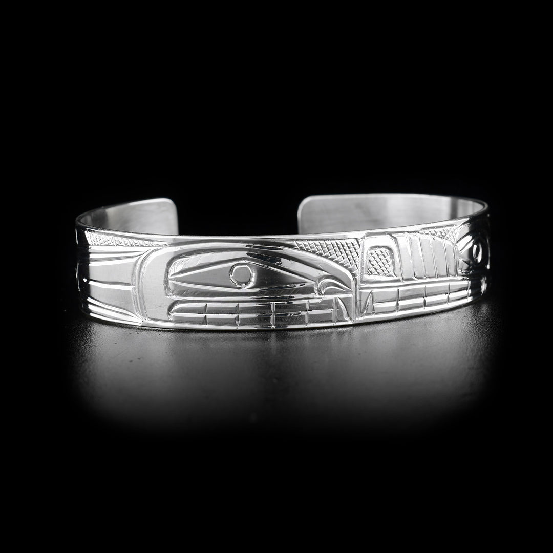 This Orca and Wolf bracelet cuff depicts orca and wolf snout to snout. Orca on right side. Cross-hatching background. Hand-carved by Heiltsuk artist Reg Gladstone.