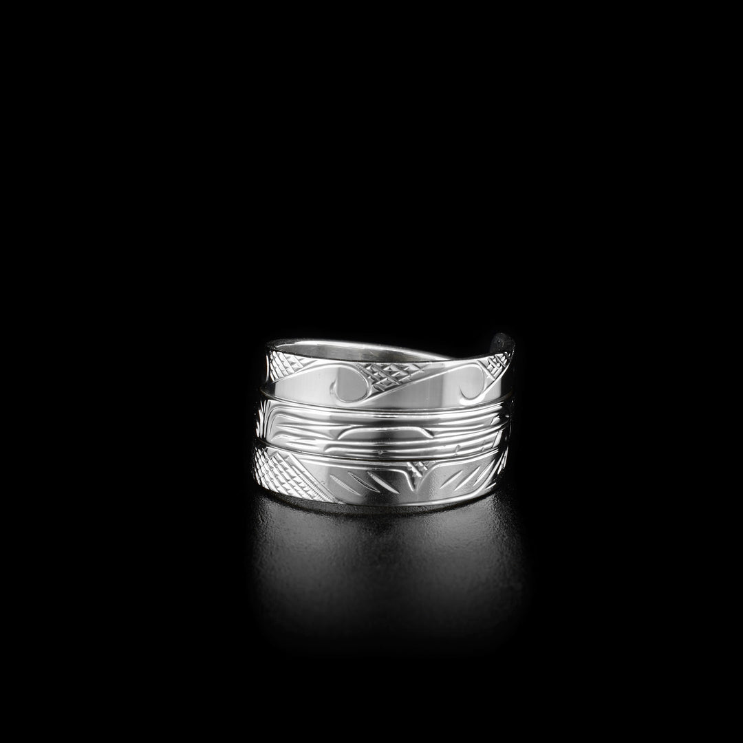Front view of ring. Ring wraps around three times. Waves on top wrap, side view of orca’s face on middle wrap and end of orca’s tail on bottom wrap. Background is cross-hatching.