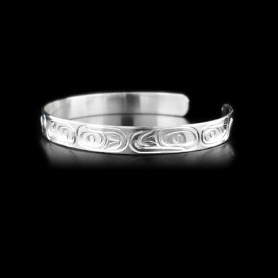 Thin sterling silver cuff bracelet depicting salmon, front left view.