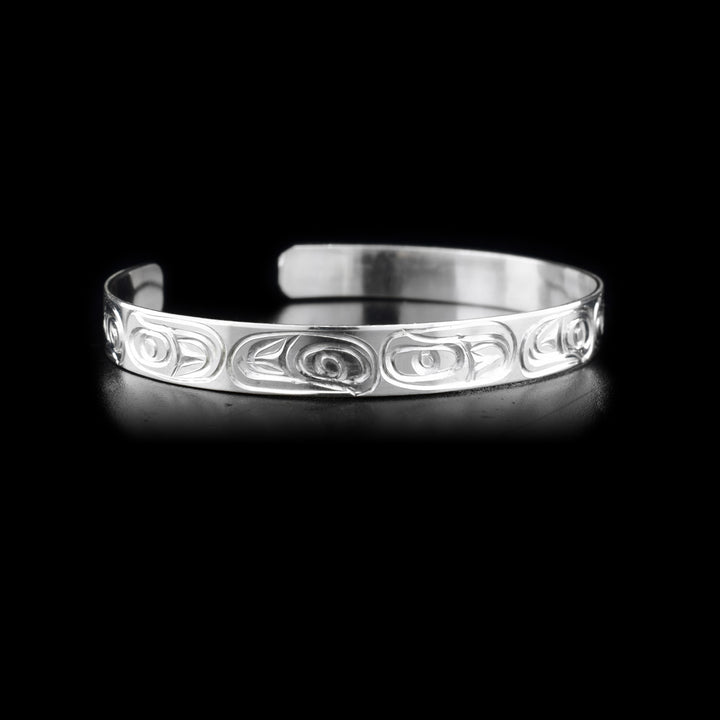 Thin sterling silver cuff bracelet depicting salmon, front right view.