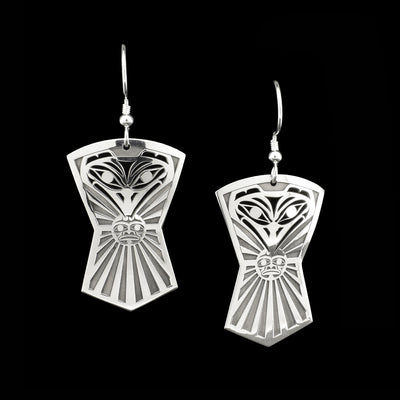 Sterling silver pierced dangle earrings. Both earrings in shape of Indigenous shield and depict front view of raven’s head with sun in beak.
