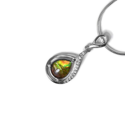 Sterling silver frame looks like ribbon dropping down and wrapping around teardrop ammolite. Top and part of side of frame has cubic zirconia. Sterling silver bail looks like small ribbon loop. Ammolite changes colour depending on how you look at it.