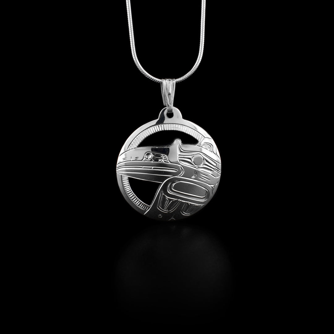 Side-view of raven’s wing and head. Silver is cut out between frame and raven. Pendant has been cut out of silver, giving the edges an almost graphic look.