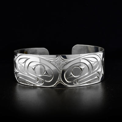 Sterling silver cuff bracelet featuring two eagle heads back-to-back. Textured background with carved designs. By Kwakwaka’wakw artist Paddy Seaweed.
