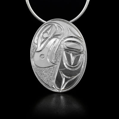 Oval sterling silver pendant featuring eagle with textured background. Hidden bail on back. By Kwakwaka’wakw artist Paddy Seaweed.