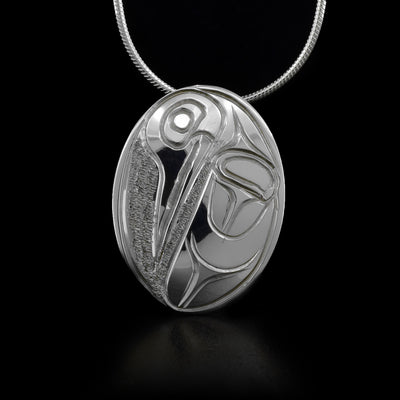 Oval sterling silver pendant featuring hummingbird with textured background. Hidden bail on back. By Kwakwaka’wakw artist Paddy Seaweed.