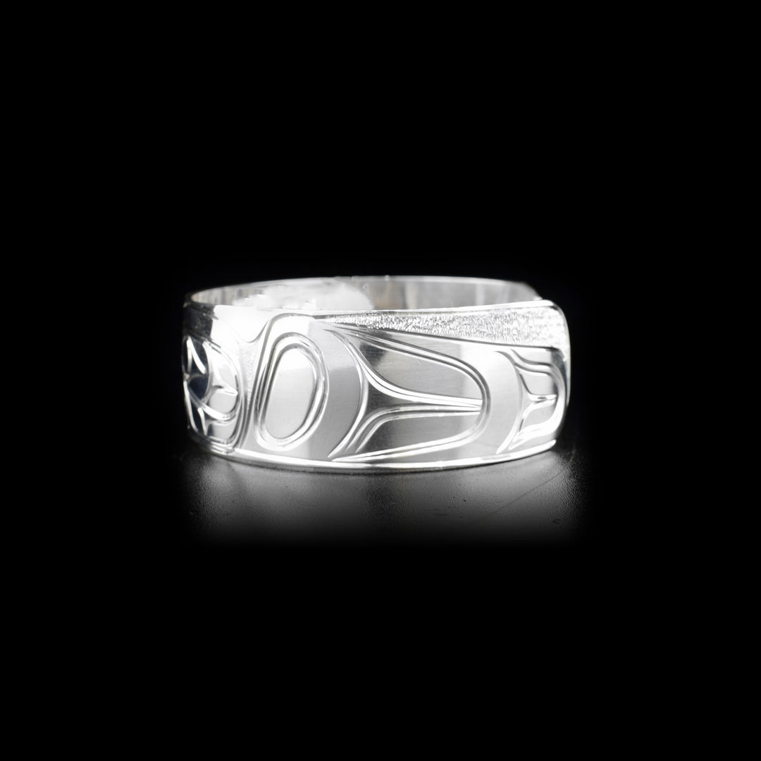 Left side of sterling silver cuff bracelet featuring raven and sun.