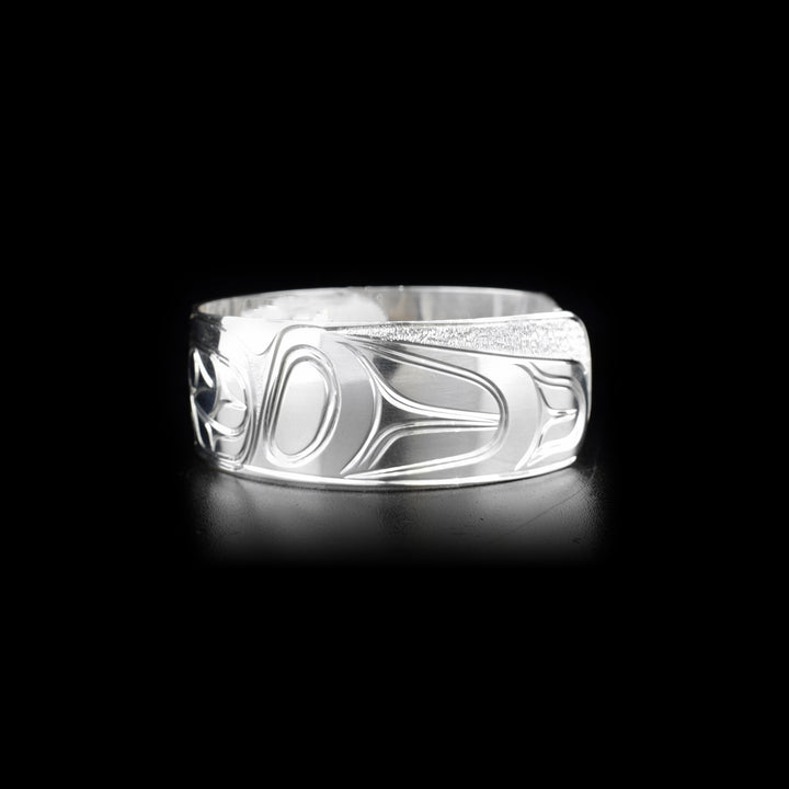 Left side of sterling silver cuff bracelet featuring raven and sun.