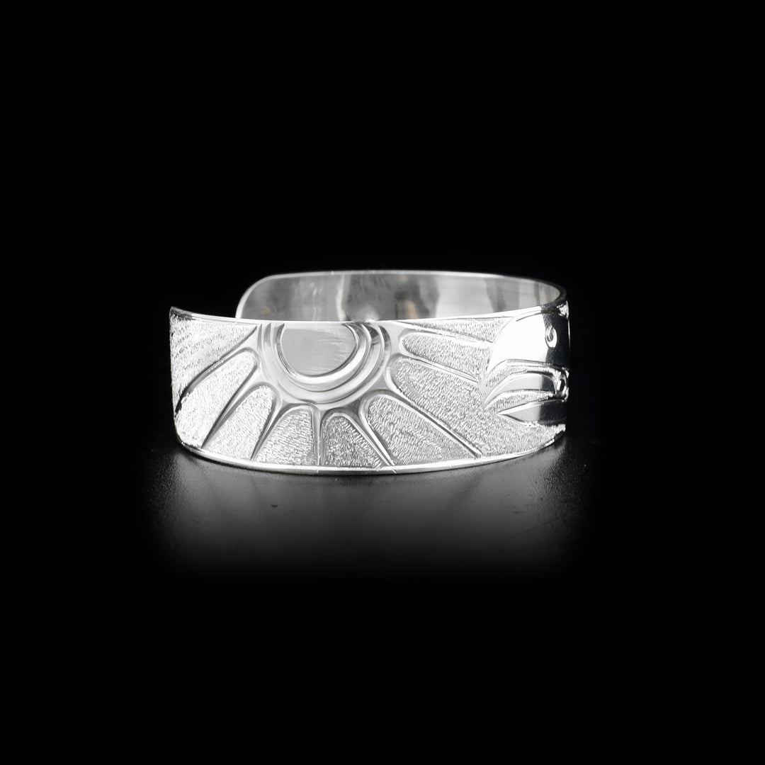 Right side of sterling silver cuff bracelet featuring raven and sun.
