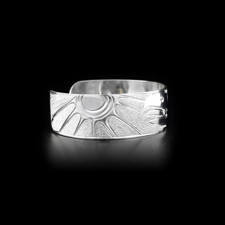 Right side of sterling silver cuff bracelet featuring raven and sun.