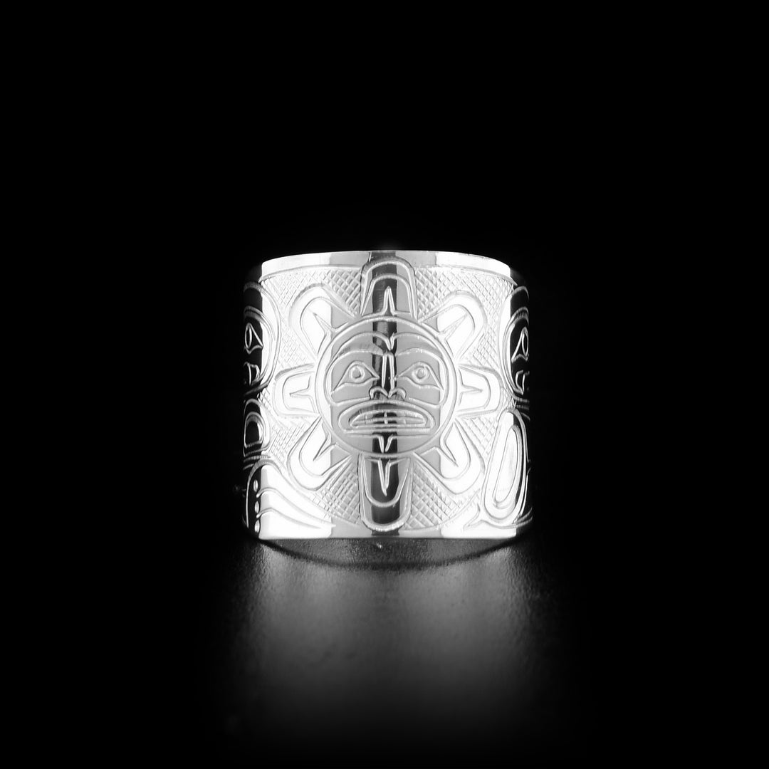 Front of ring with meticulously carved sun with face and eight rays. Background is cross-hatching. Hand-carved by Coast Salish artist Travis Henry.