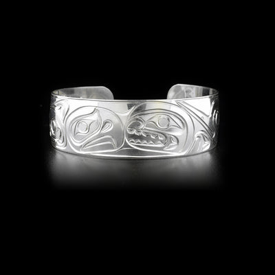 Front of sterling silver cuff bracelet featuring eagle and orca heads facing each other.