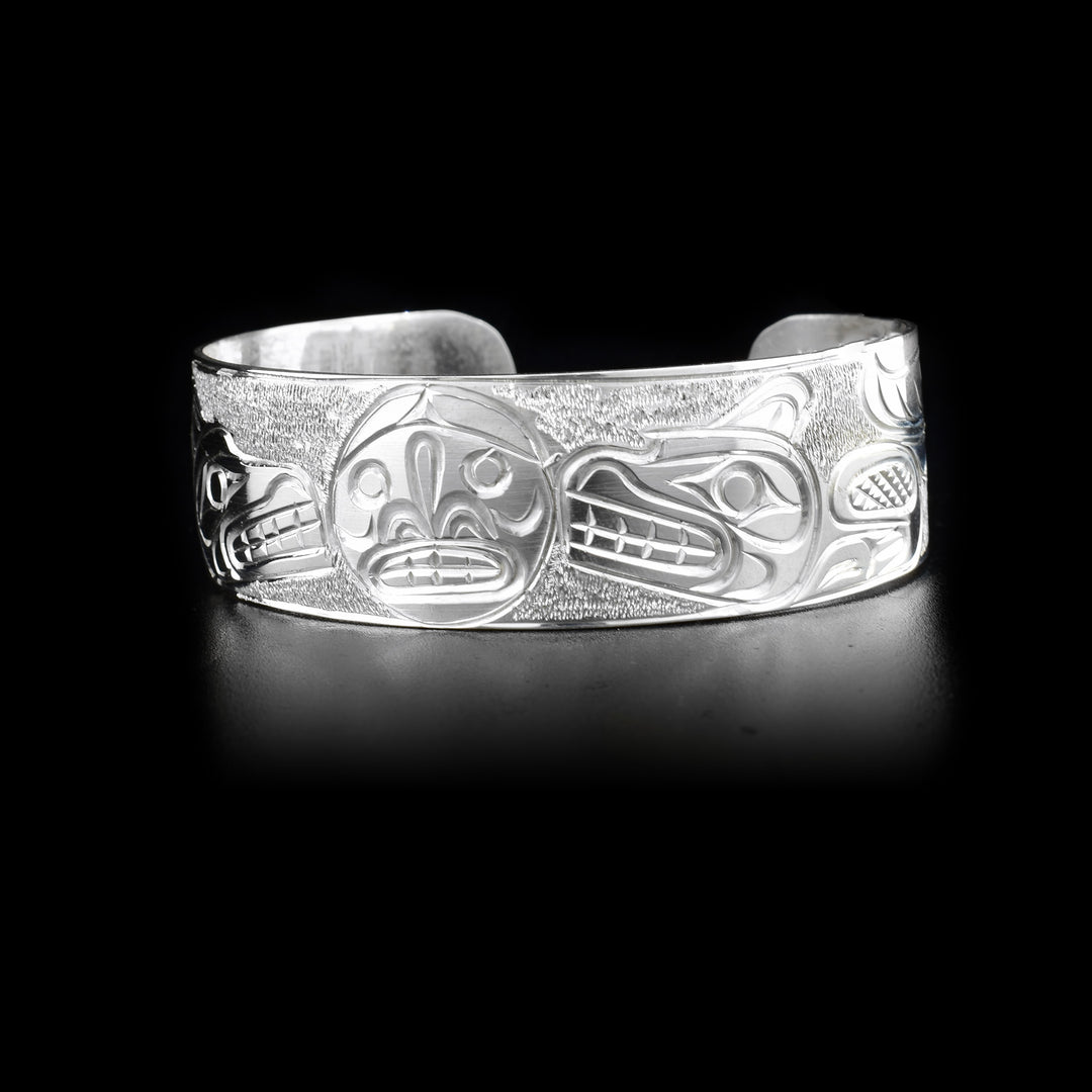 Sterling silver cuff bracelet depicting two wolves facing the moon in the center.