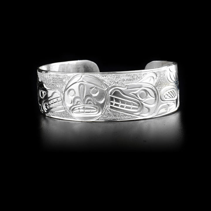 Sterling silver cuff bracelet depicting two wolves facing the moon in the center.