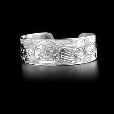 Sterling silver cuff bracelet depicting two wolves facing the moon in the center.