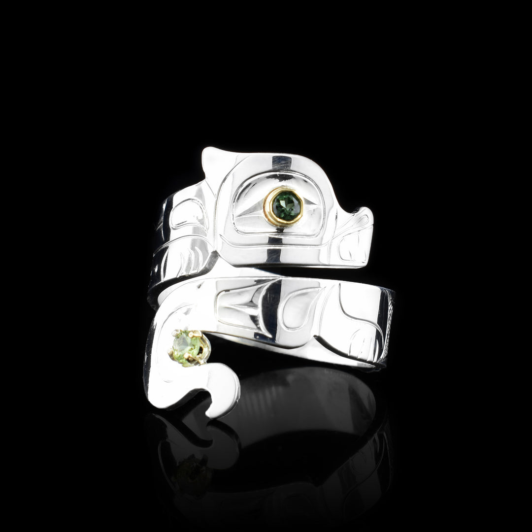 This Wolf ring has a sterling silver wide band that wraps around the finger twice. The top band  is carved to depict the head of the Wolf and the bottom one depicts its tail. There is a tourmaline gem that is embedded into the eye of the legend. Peridot is wrapped at the bottom of the tail.