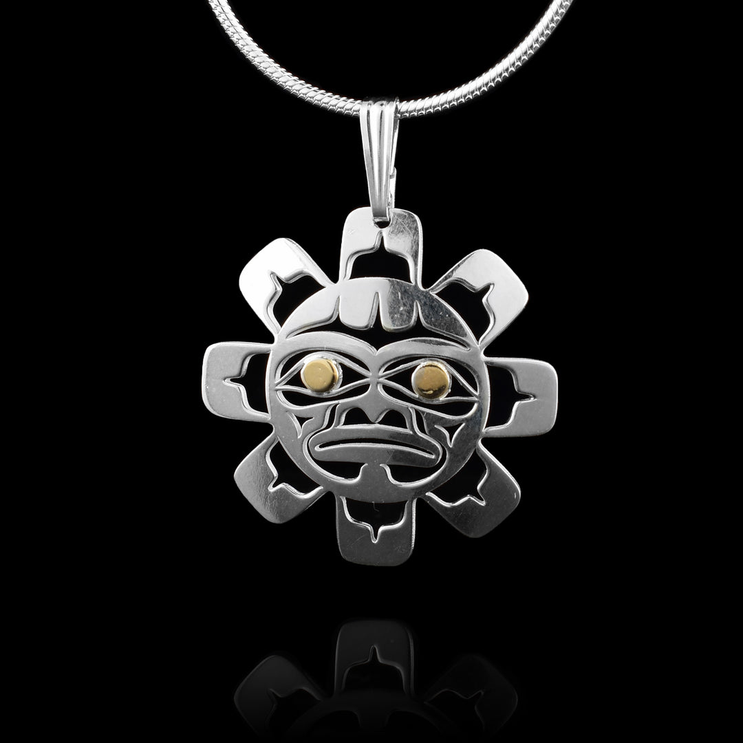 This stunning pendant features a sterling silver sun, meticulously carved and cut out to showcase an authentic indigenous artistic style. The sun's gaze is brought to life with captivating 14k gold eyes, adding a touch of warmth to this intricate design. 