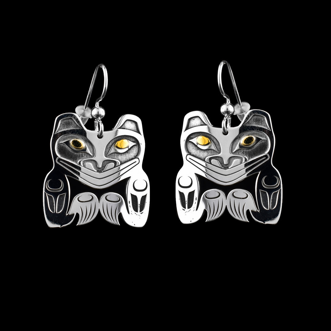 Sterling silver bear dangle earrings by Tahltan artist Grant Pauls, featuring 14K yellow gold eyes and bold, hand-carved detailing.