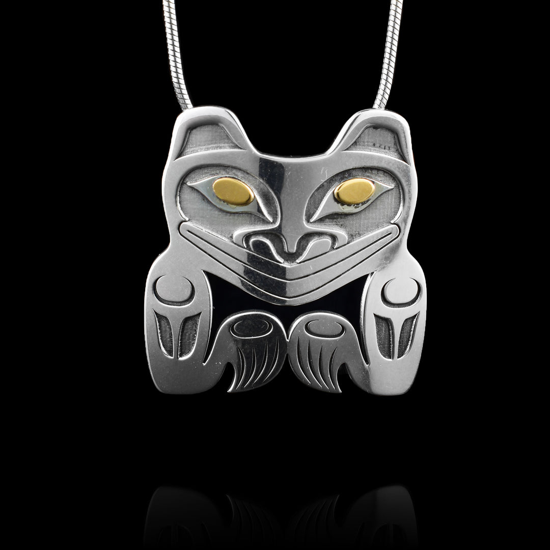Handcrafted sterling silver bear pendant by Grant Pauls, accented with 14K yellow gold eyes and striking carved detail.