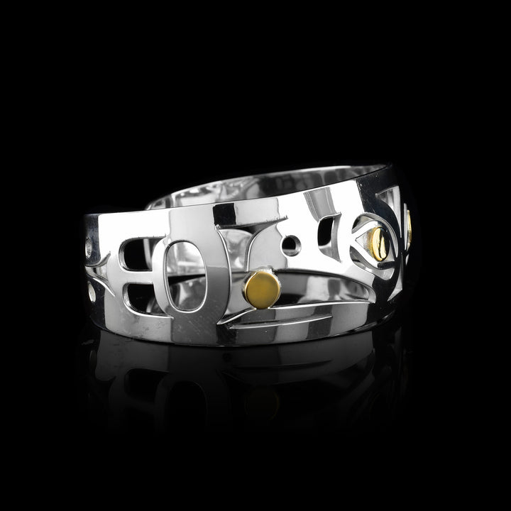 this Grant Pauls Raven cuff bracelet. Handcrafted by the Tahltan artist, this sterling silver piece features striking 14k yellow gold accents in the Raven’s eyes and the ball of light.
