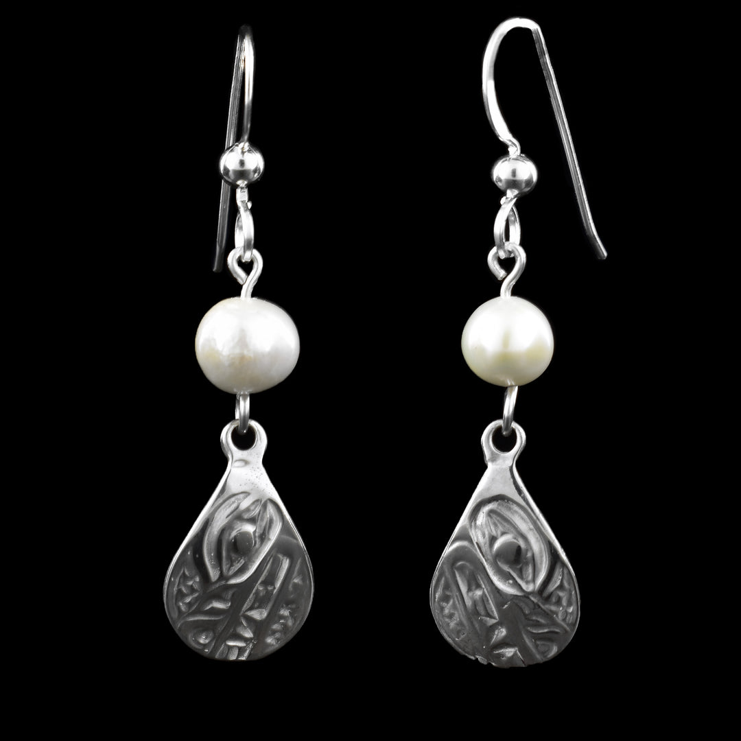 These teardrop earrings have a beautifully carved wolf design in sterling silver. Each teardrop is topped with a small freshwater pearl, which is a vibrant white. Suspended from sleek French hooks.