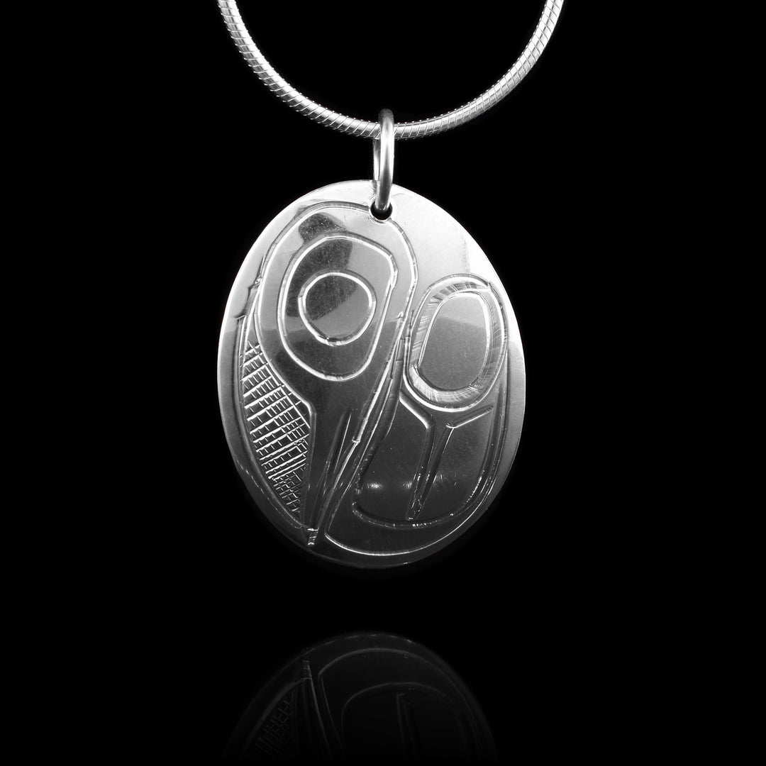 This simple silver hummingbird pendant is crafted with sterling silver. The head is tucked down into the wing with a cross hatch of sky between the eye and beak.