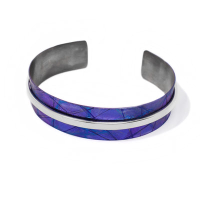 0.56” wide cuff made of anodized titanium. Colour is purple blue. Thin strip of sterling silver goes all the way across the middle, contrasting the blue.