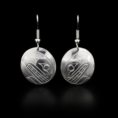 Domed, oval sterling silver earrings with orca heads facing downwards. Cross-hatching background. Dangle earrings hand-carved by Coast Salish artist Travis Henry.