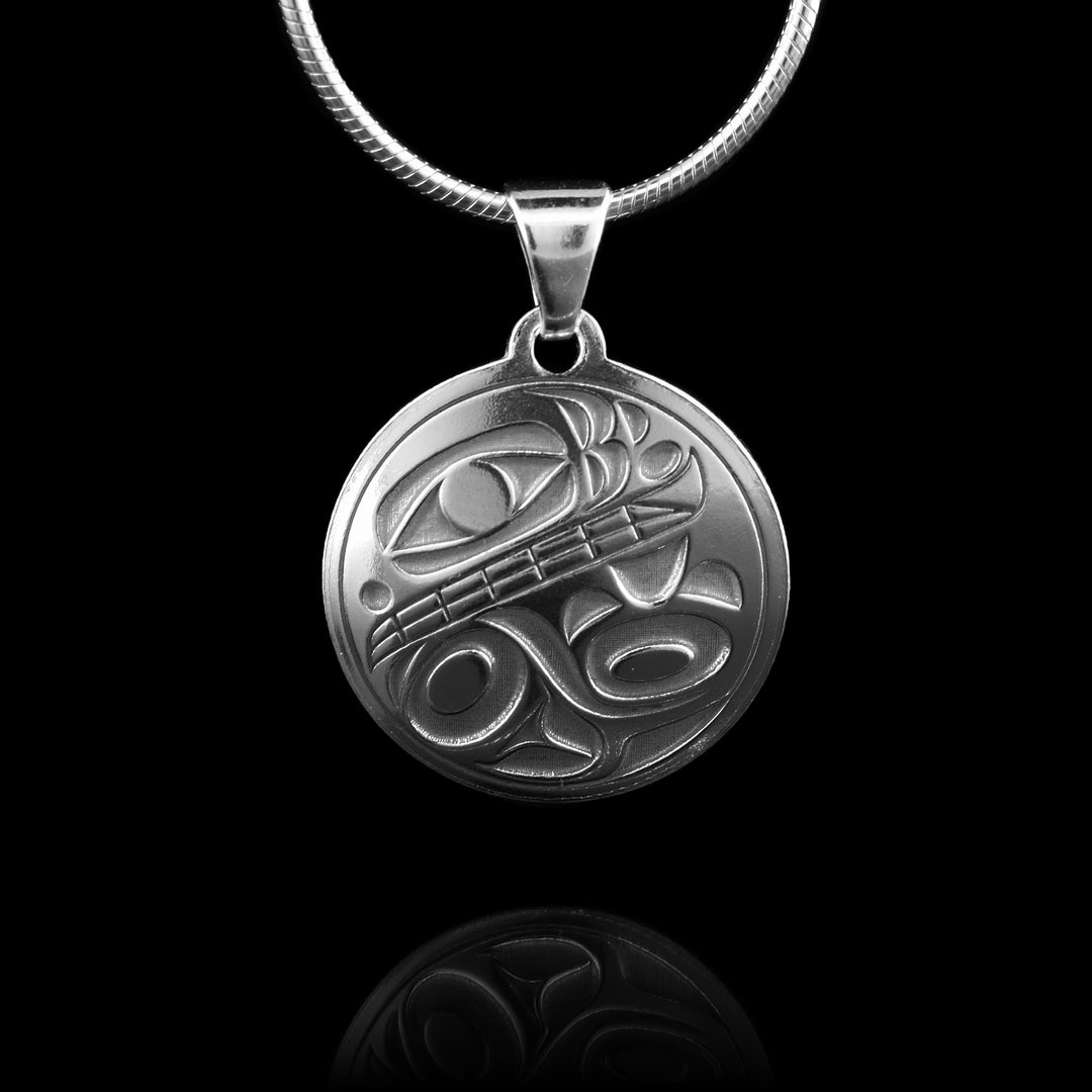 Thissmall orca silver pendant features a circular design crafted from sterling silver. A side-profile depiction of the orca is cast into the pendant, with the top half showcasing the eye, mouth with visible teeth, and the distinct lower jaw.