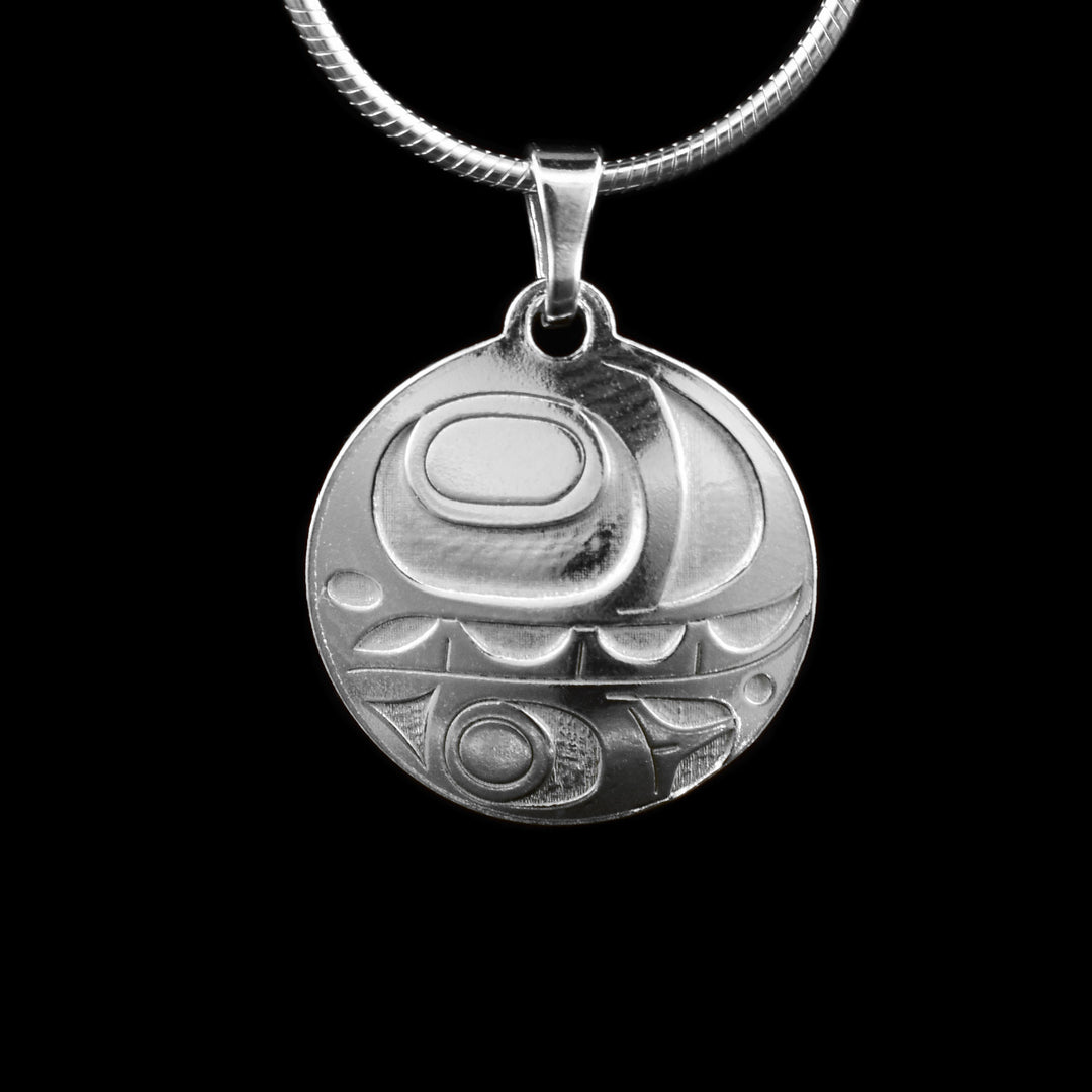 This orca silver pendant features a circular design crafted from sterling silver. A side-profile depiction of the orca is cast into the pendant, with the top half showcasing the eye, mouth with visible teeth, and the distinct lower jaw.