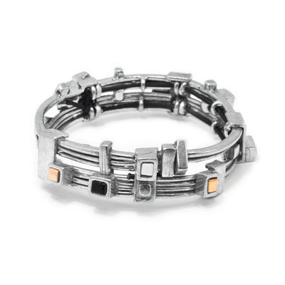 This glass bangle bracelet has thin, pewter bands that are stacked on each other. There are two, separate bands that are made from four thin bands each to make this piece. There are gold plated cubes, as well as black and white glass ones that are framed in pewter around the band.