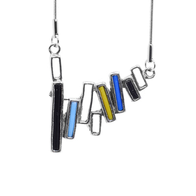 This pewter pendant necklace is made of many thin, cutout, pewter rectangles that are attached together to form a long, horizontal shape. There are black, yellow, turquoise and blue glass in some of the pewter rectangles.