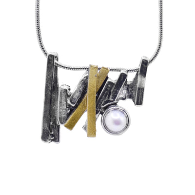 This pewter pendant is a long, bar pendant that is made up of several gold plated and pewter strips. The strips are connected at different angles and give the piece a jagged appearance There is a freshwater pearl held in the pendant..