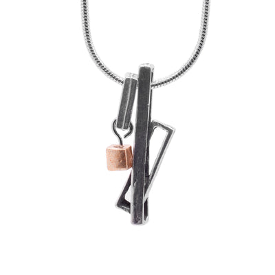 This unique pewter pendant is made up of three cutout, pewter rectangles. A long rectangle drops down with another one linked through it at an angle. Beside this piece is another rectangle that hangs horizontally and has a gold plated cube charm hanging from it.