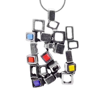 This pewter pendant is roughly square shaped and is made of many cutout, pewter squares that are attached together at different angles. There are purple, yellow, blue and red colored glass pieces that are in the center of some of the squares.