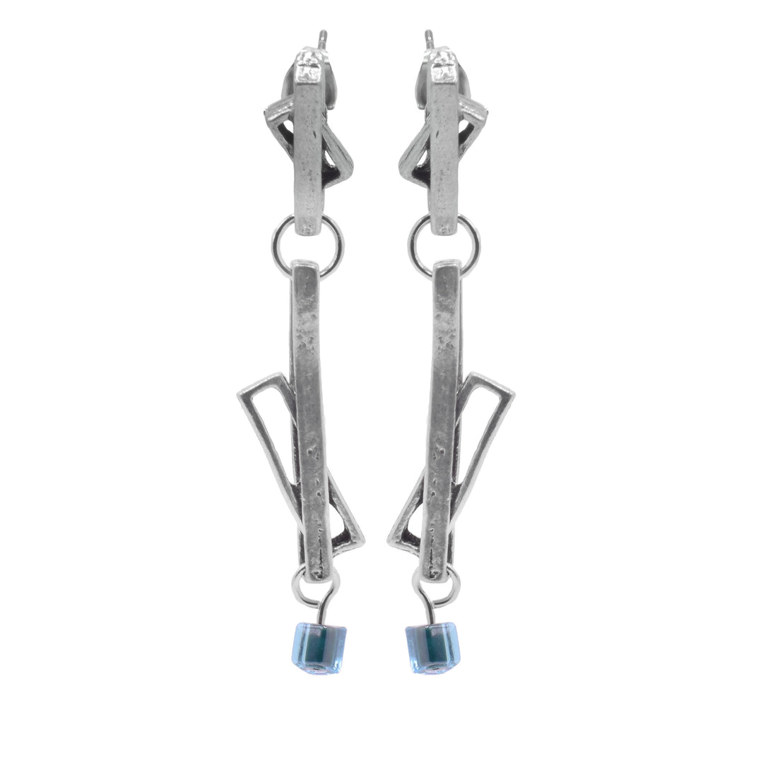 These glass drop earrings have multiple cutout, pewter rectangles that are connected with a small link. Some of the rectangles link through the other to form abstract shapes. The earrings are long and made of two separate dangling pieces and there are turquoise glass cubes attached to the bottom.