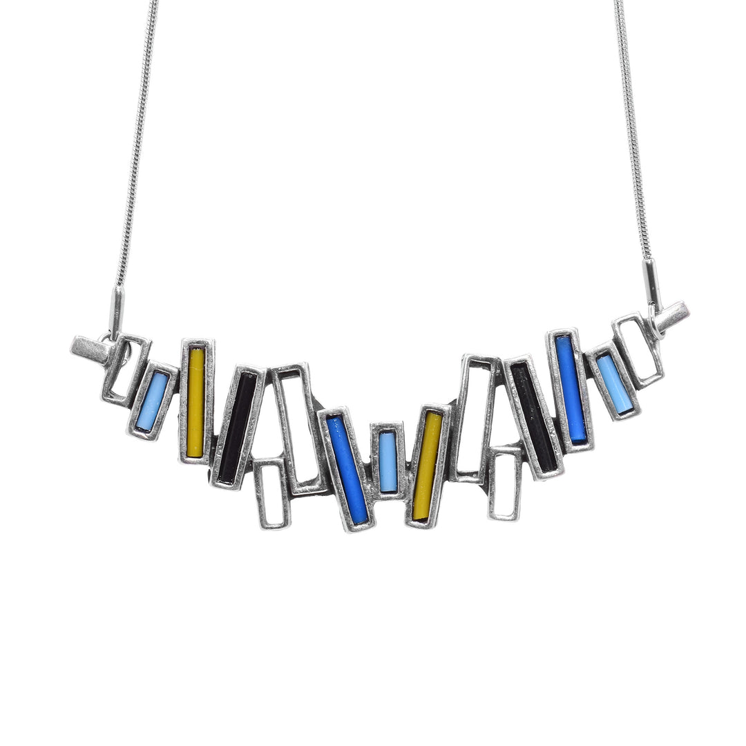 This bar pendant necklace is made up of vertical, cutout rectangles made from pewter. The pieces are connected in an abstract pattern and form a horizontal bar. There are blue, turquoise, yellow and black pieces of glass in some of the pewter rectangles.