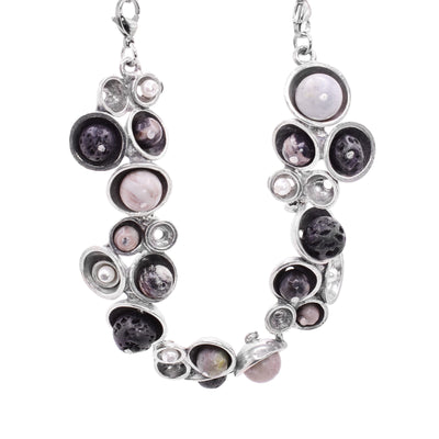 This pewter pendant has pewter, hollow half circles of different sizes with freshwater pearls and black, lava rocks held in them. The pearls and rocks are only on the bottom half f the necklace.