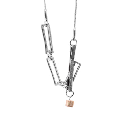 This large chain necklace has long, thin rectangle chain links made from pewter that are connected together at the bottom of the necklace. There is a gold plated  gold cube charm dangling from the large chain links.