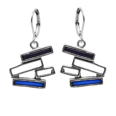 The pewter, abstract earrings have chunky hangs made of multiple thin, rectangle and cutout pieces of pewter. The rectangles are stacked horizontally at different angles and the top ones are filled with black glass and the bottom one is filled with blue glass.