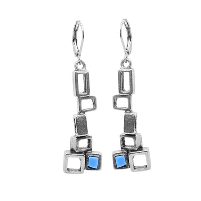 These pewter drop earrings are made up of several cutout, pewter squares that connect horizontally and drop down. At the bottom there is a cluster of three squares and one of them has a turquoise glass panel in the center of it.