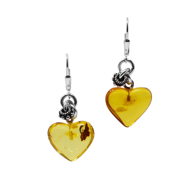 Heart-shaped amber hangs from sterling silver lever-back hooks. Patterned silver ring adornments hang in a cluster above the hearts.