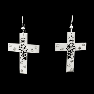 Pierced dangle earrings by Tahltan artist Grant Pauls. Flat crosses with bears in center and bear paw prints all over.