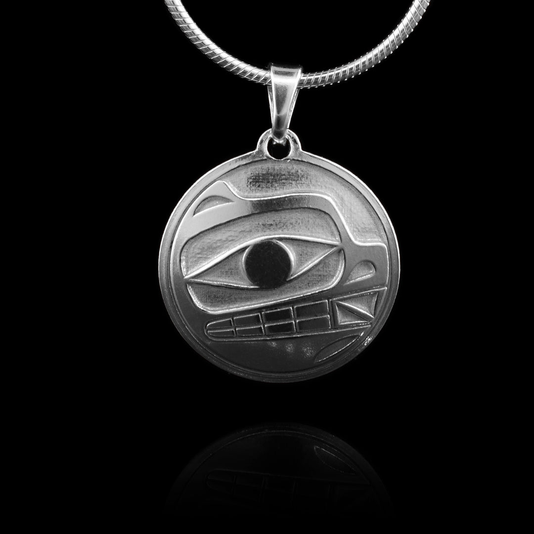 This bear silver pendant has a circle shape made from sterling silver. There is a depiction of the bear cast into the pendant at a side profile. The top half consists of the eye, mouth with teeth showing and nose.