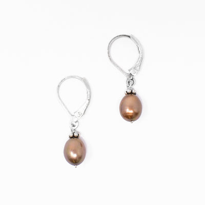 Lever-back earrings with vertical oval brown freshwater pearls. Pearls are framed by oxidized silver adornments on top. Each earring measures 1.13” x 0.25” including hook.