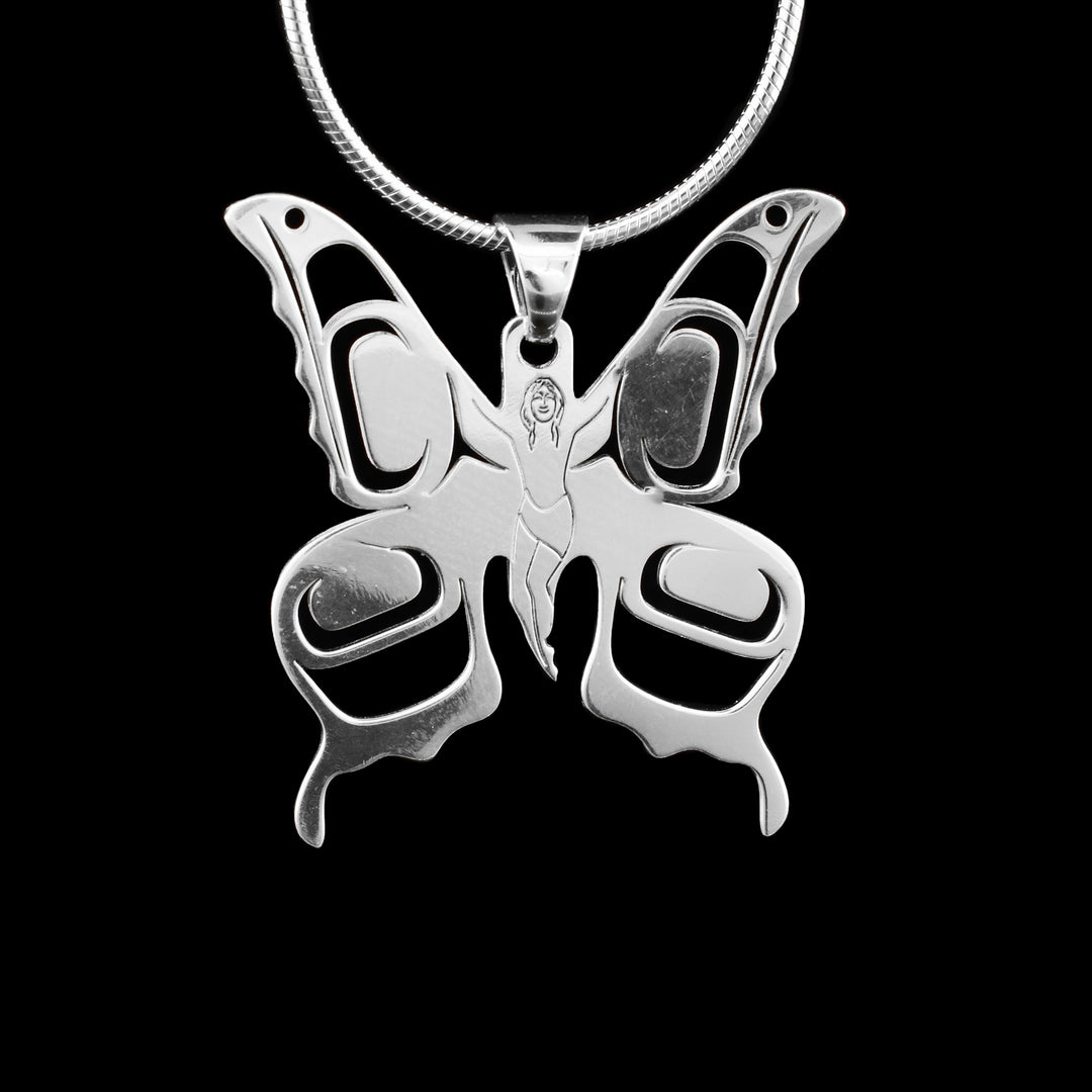 This pendant is crafted from sterling silver and designed in the shape of a butterfly. The wings feature delicate cutout patterns, while the body is intricately carved to depict a small human figure, adding a unique and symbolic element to the piece.